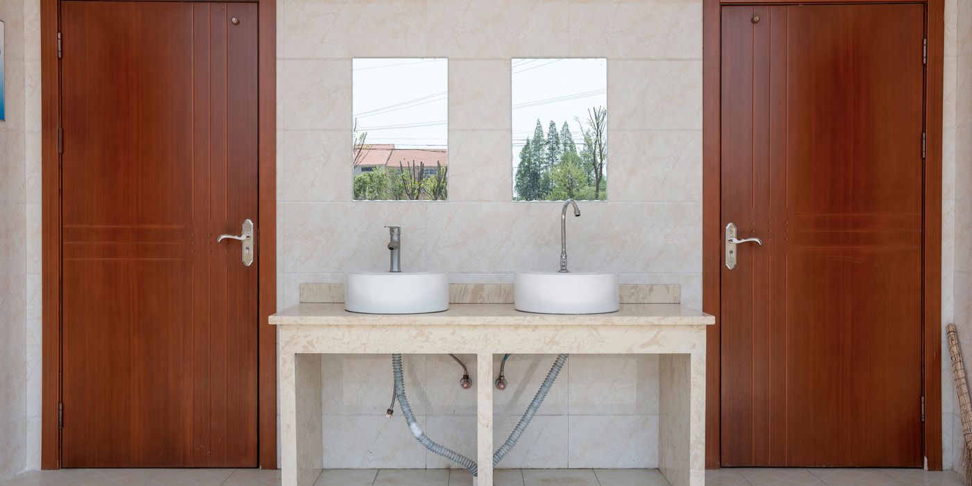 Bright modern corporate washroom with twin sinks and hygienic supplies