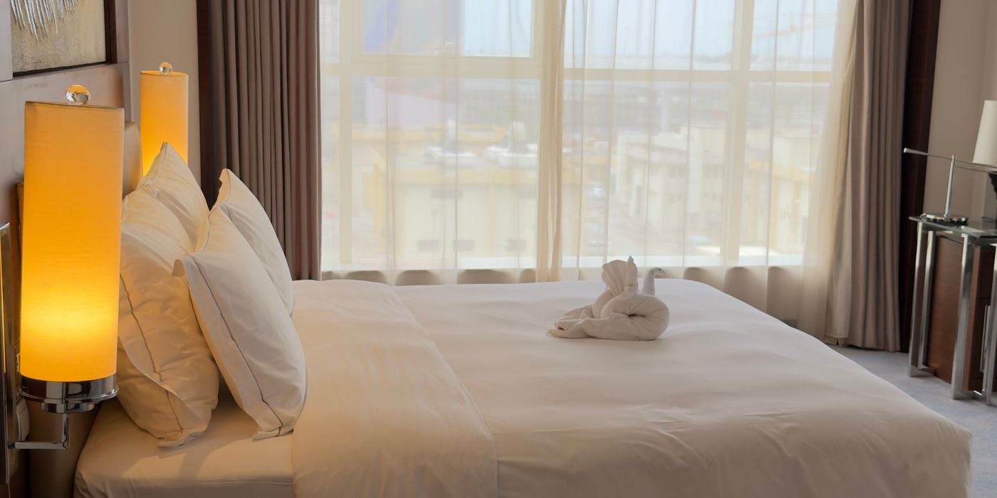Luxury hotel bedroom with large window, premium bedding and neatly arranged amenities